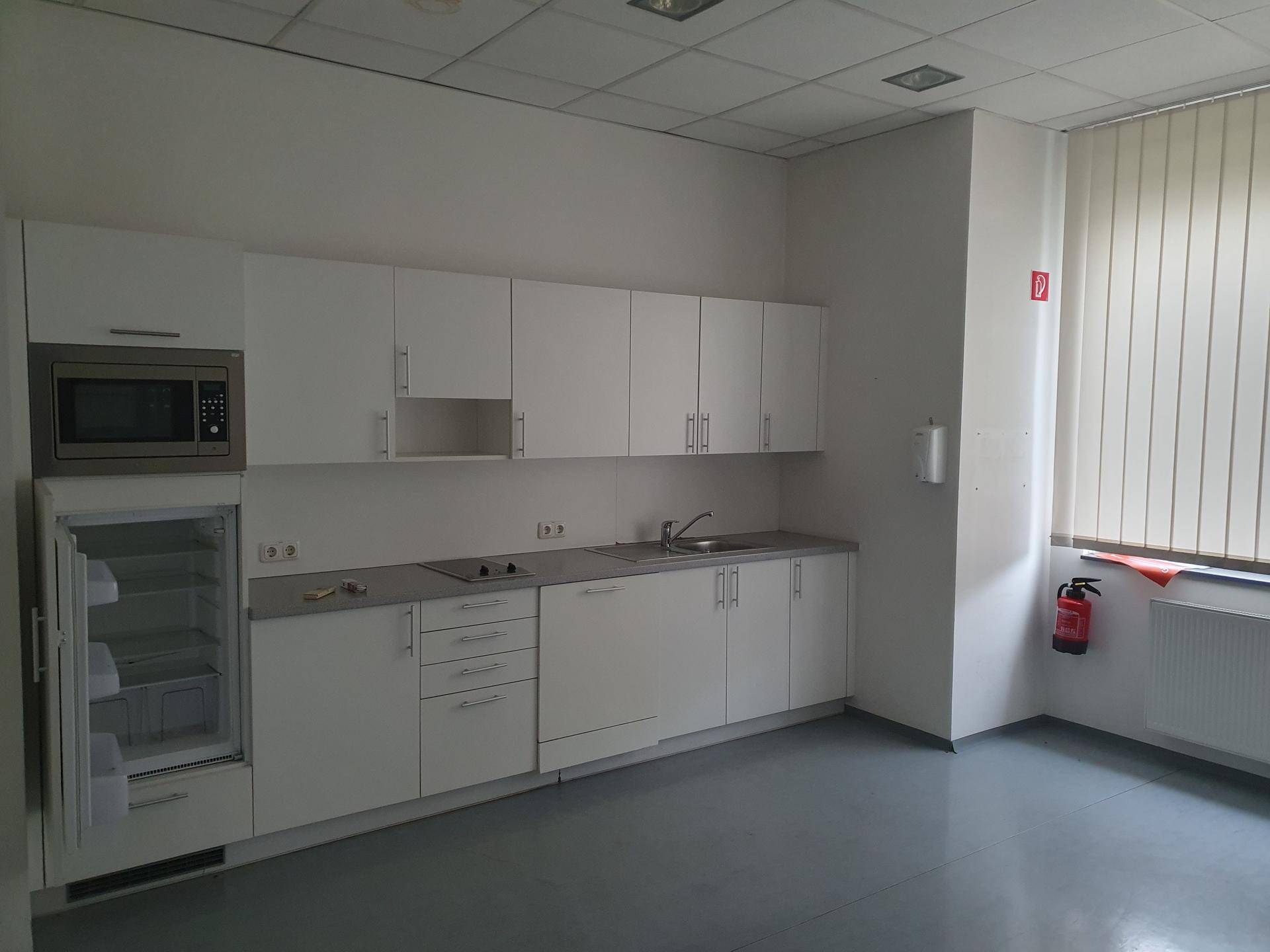 Funktionale Küchenzeile mit weißen Schränken, integrierten Geräten und Fenster.