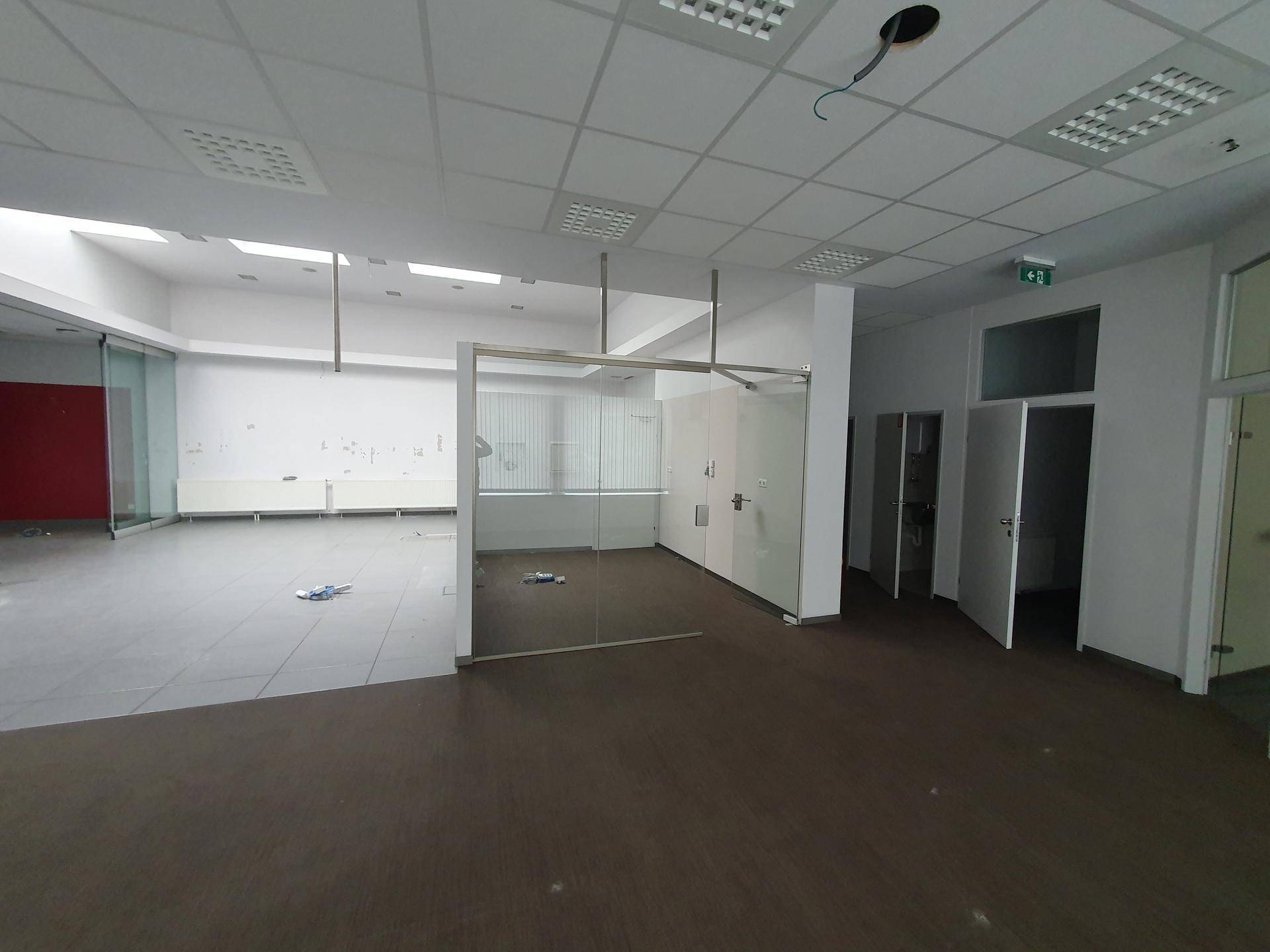 Großzügiger Bürobereich mit Glaswänden und dunklem Boden, bietet flexible Raumgestaltung.
