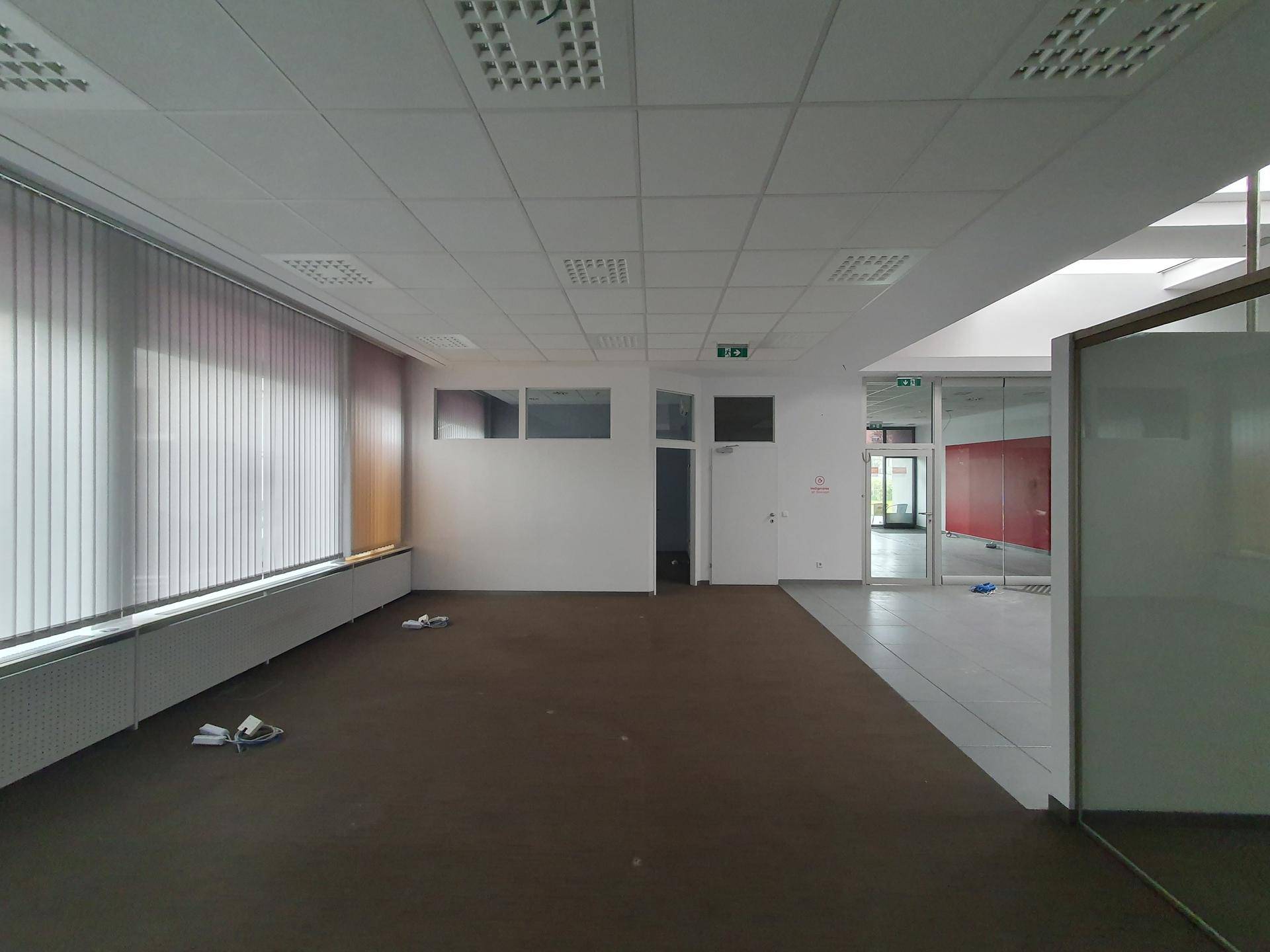Geräumiger Büroraum mit Teppichboden und großen Fenstern, bietet viel Tageslicht.
