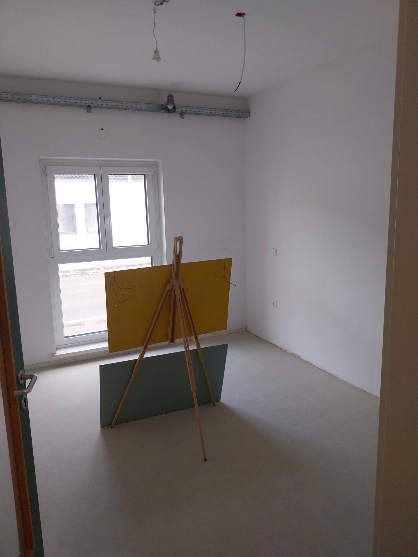 Raum im Bau mit einem großen Fenster und einer provisorischen Abdeckung auf dem Boden.