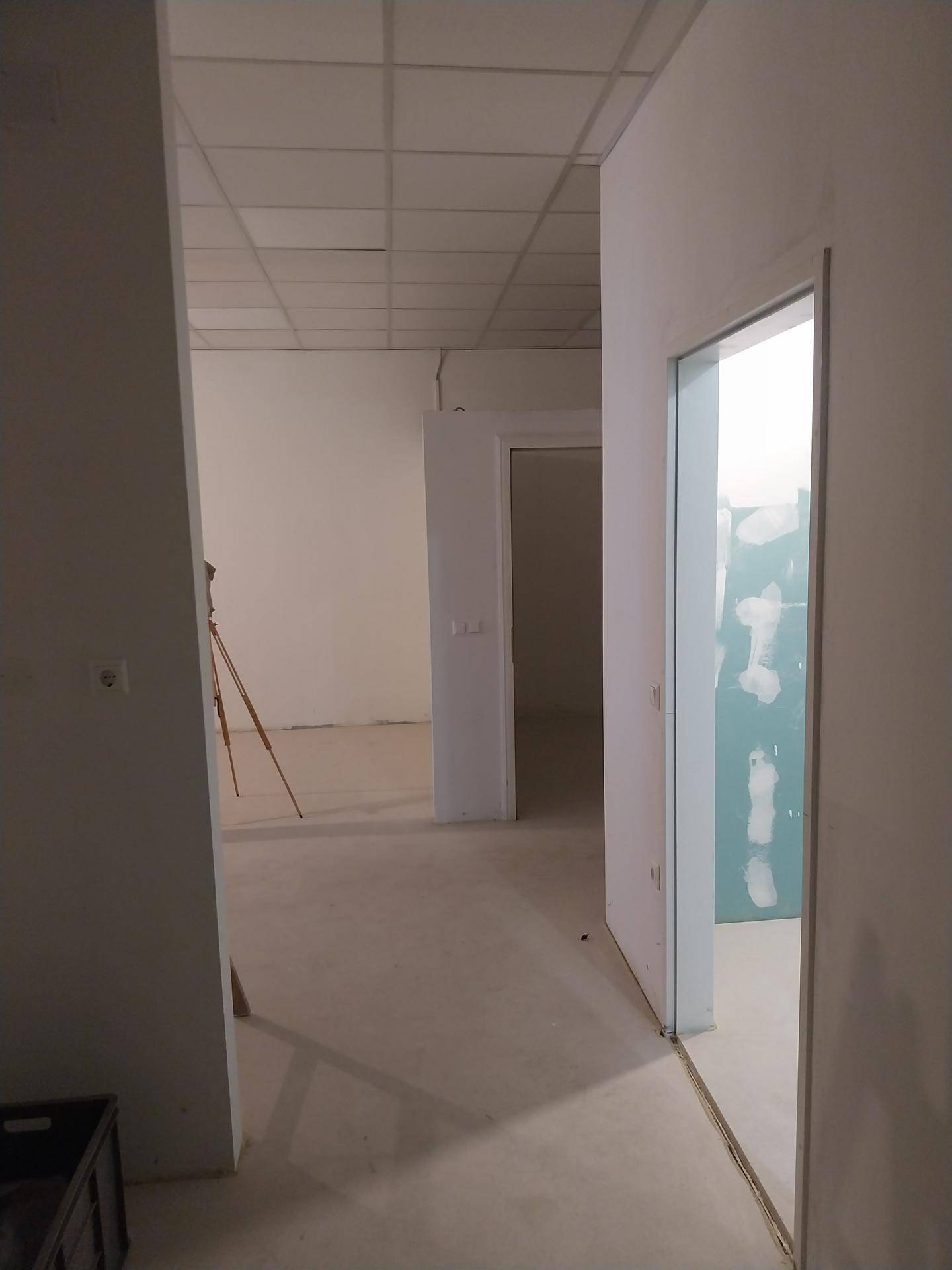 Flur im Bau mit Blick auf mehrere offene Räume und eine abgehängte Decke.