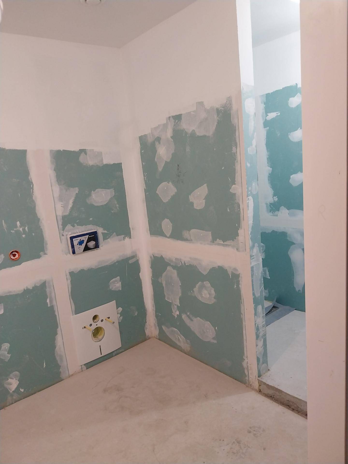 Badezimmer im Bau mit Gipskartonwänden und vorbereiteten Installationen.