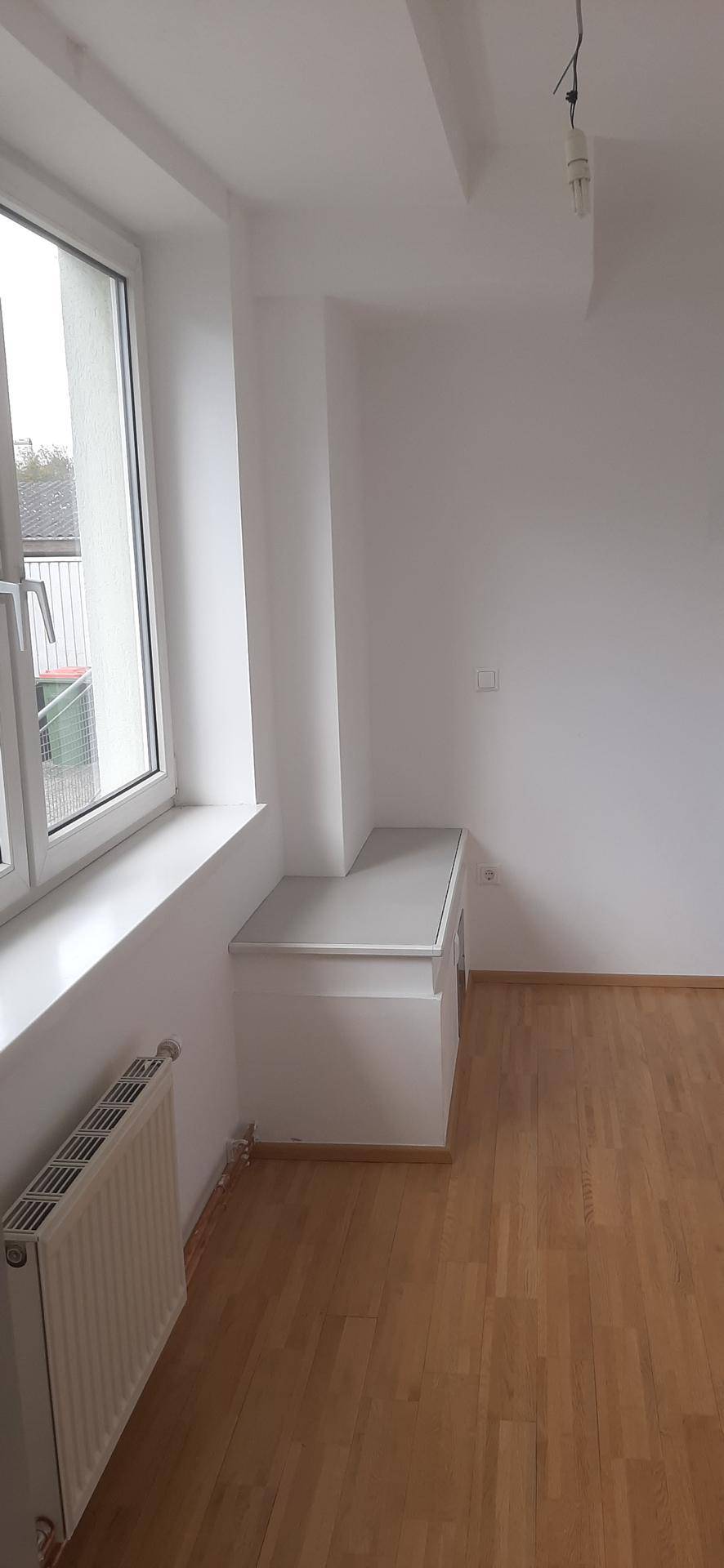 Helles Büro mit großem Fenster, Heizkörper und einer weißen Ablagefläche unter dem Fensterbrett.