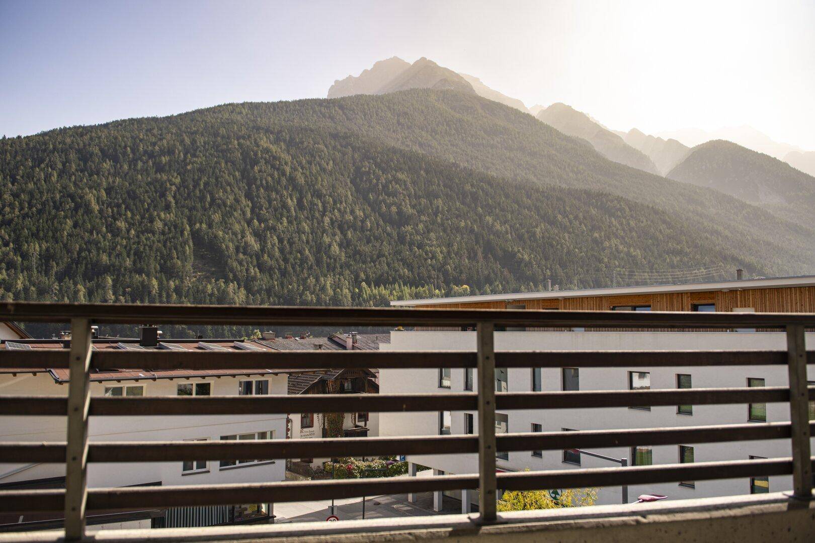 Balkon mit Blick auf die umliegenden Gebäude und die majestätische Berglandschaft im Hintergrund.