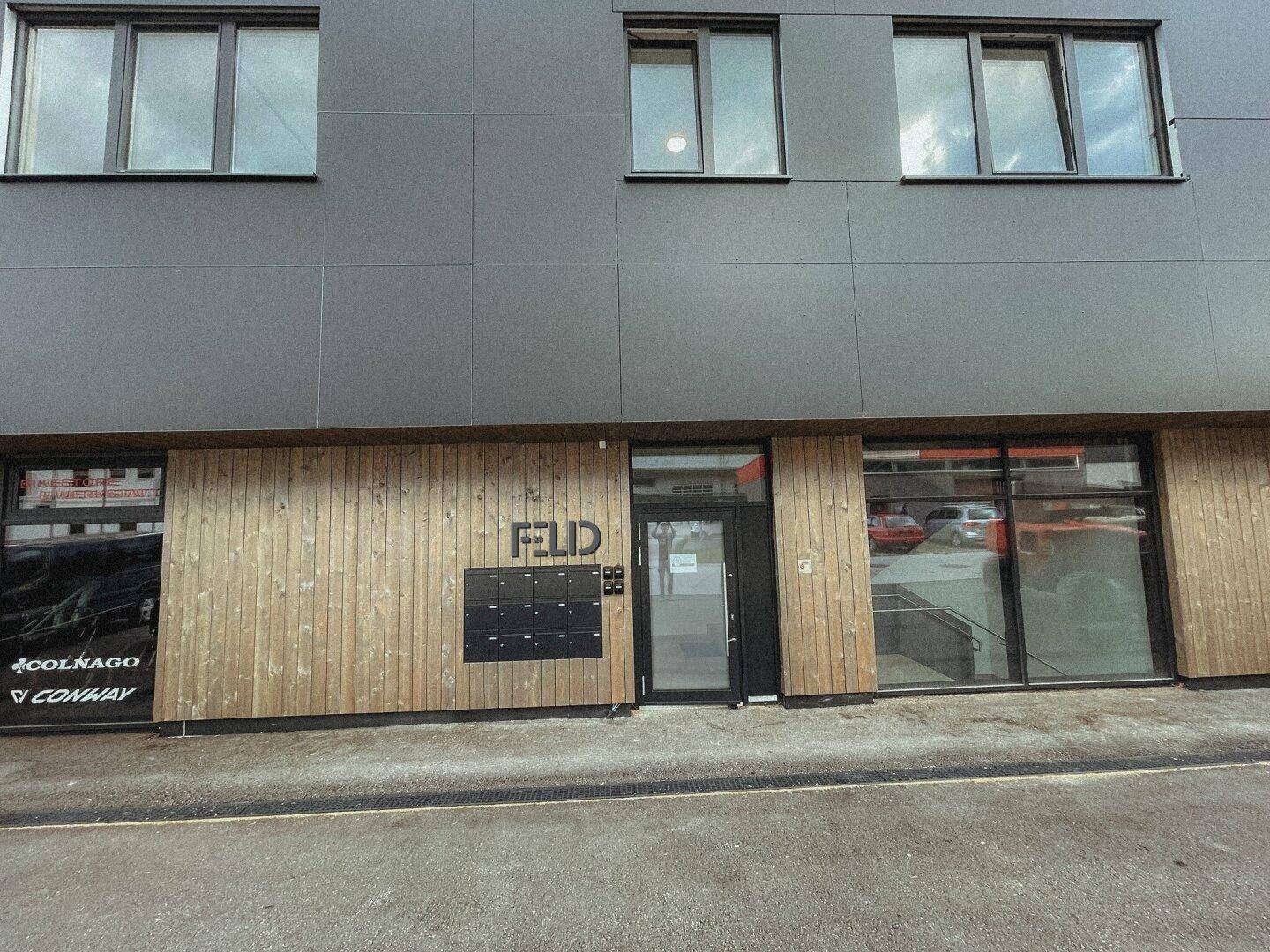 Eingangsbereich eines modernen Gebäudes mit Holzverkleidung, Briefkästen und dem Schriftzug "FELD".