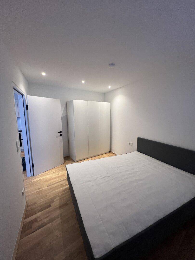 Helles Schlafzimmer mit Holzboden, einem Doppelbett und einem weißen Kleiderschrank.