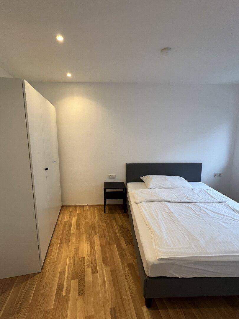 Gemütliches Schlafzimmer mit Holzboden, Einzelbett und weißem Kleiderschrank.