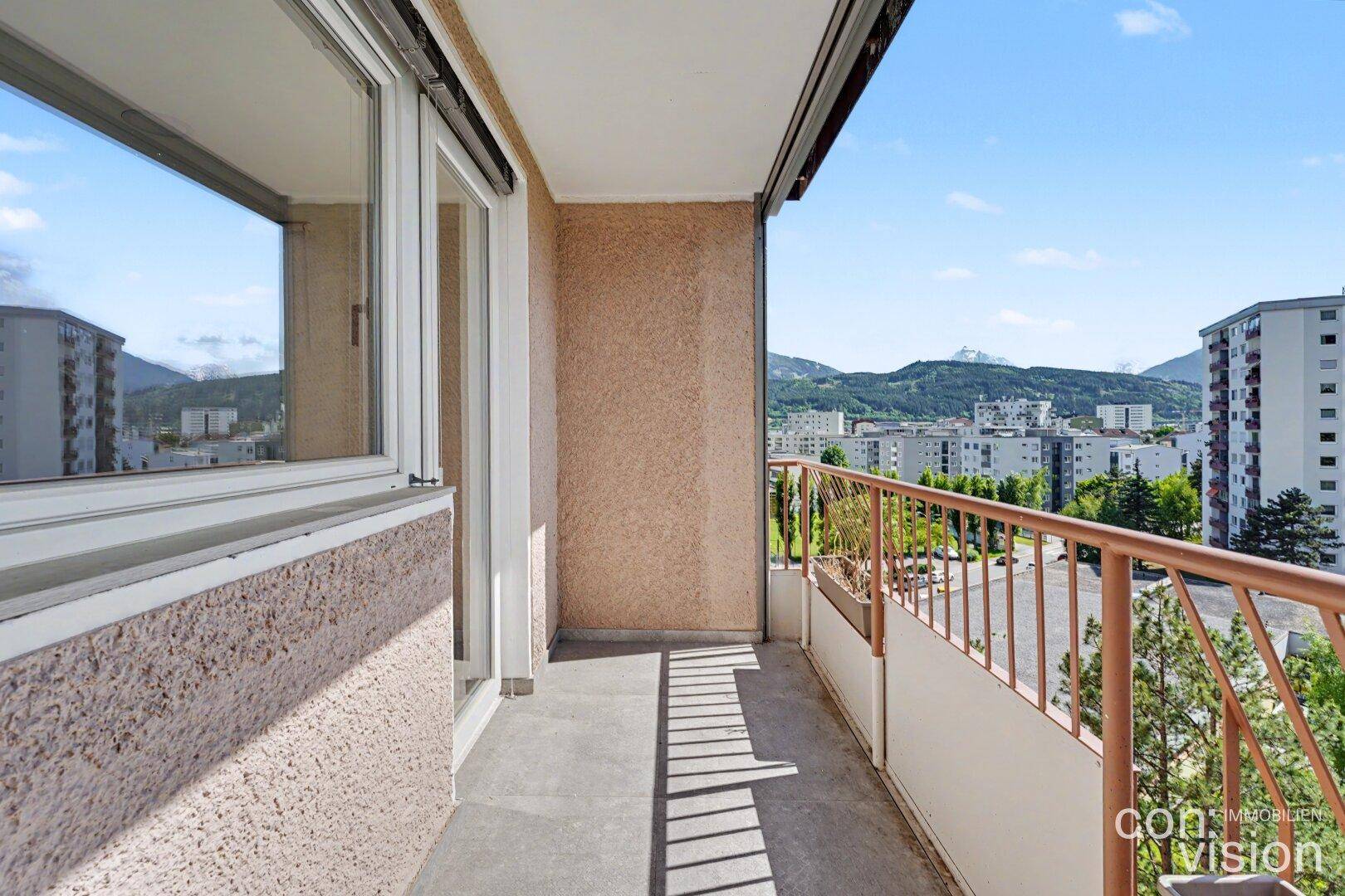 Balkon mit Metallgeländer und Blick auf die umliegende Stadt und die Berge.