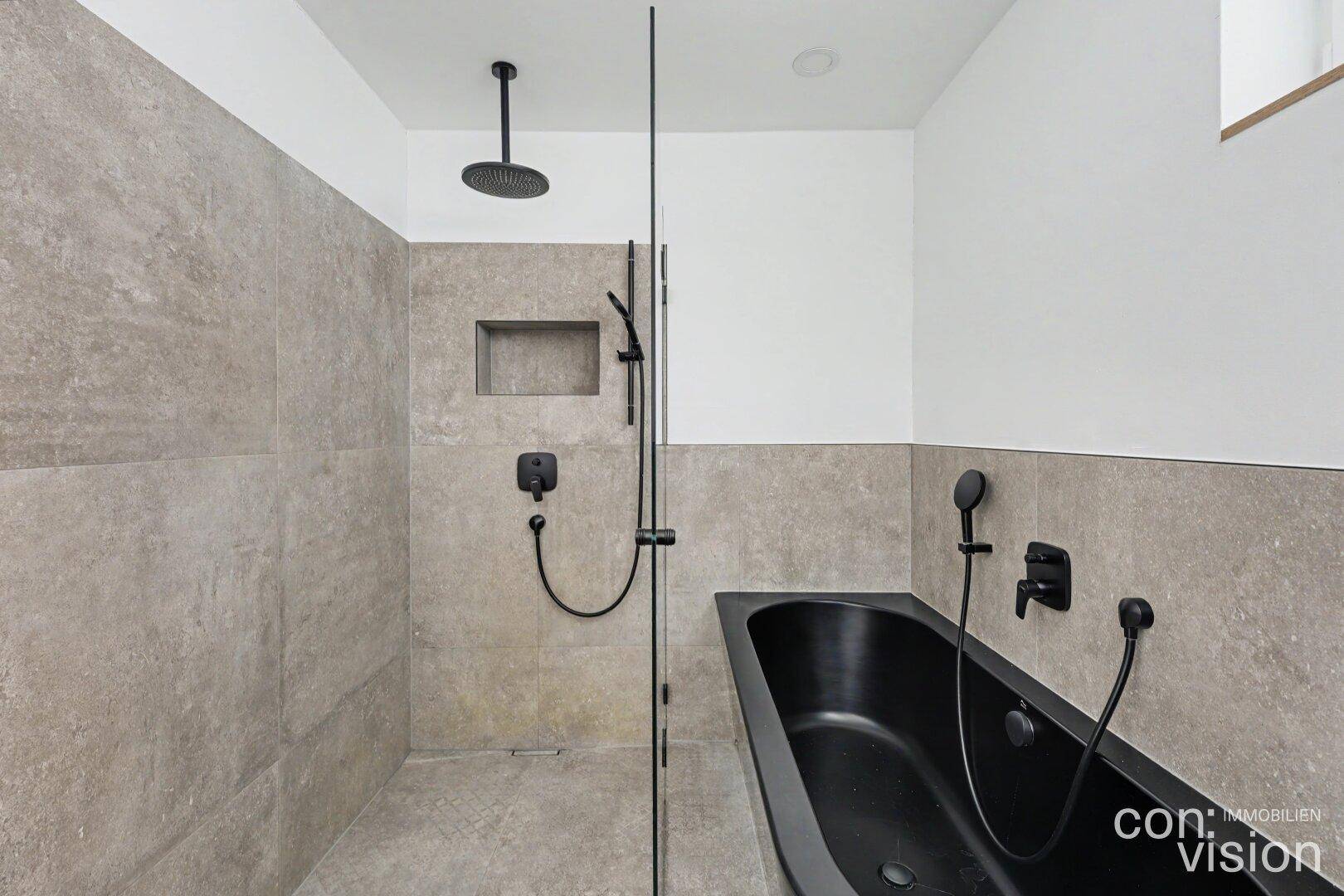 Modernes Badezimmer mit großer begehbarer Dusche, schwarzer Badewanne und grauen Fliesen.