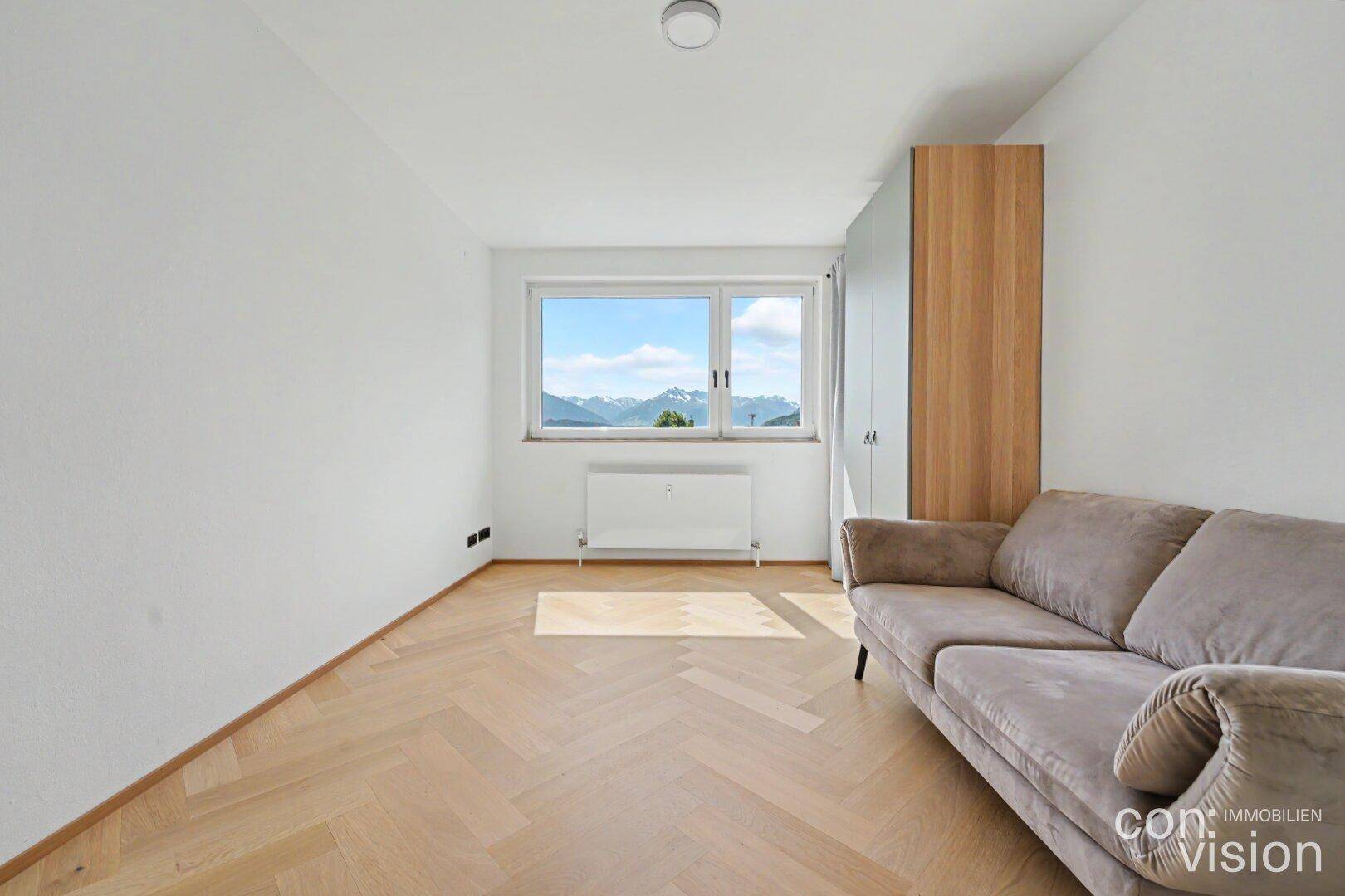 Schlafzimmer mit Fischgrätparkett, großem Fenster und Schrank, bietet Bergblick.