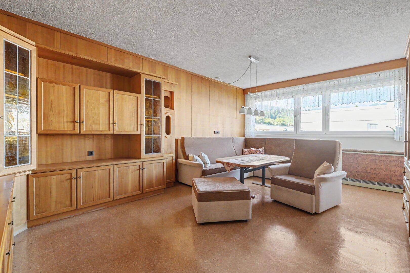 Geräumiges Wohnzimmer mit umfangreicher Holzvertäfelung, Einbauschränken und gemütlicher Sitzecke.