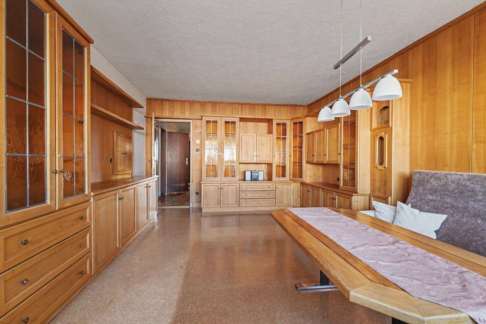 Heller Wohn- und Essbereich mit durchgehender Holzvertäfelung und großzügigen Einbaumöbeln.