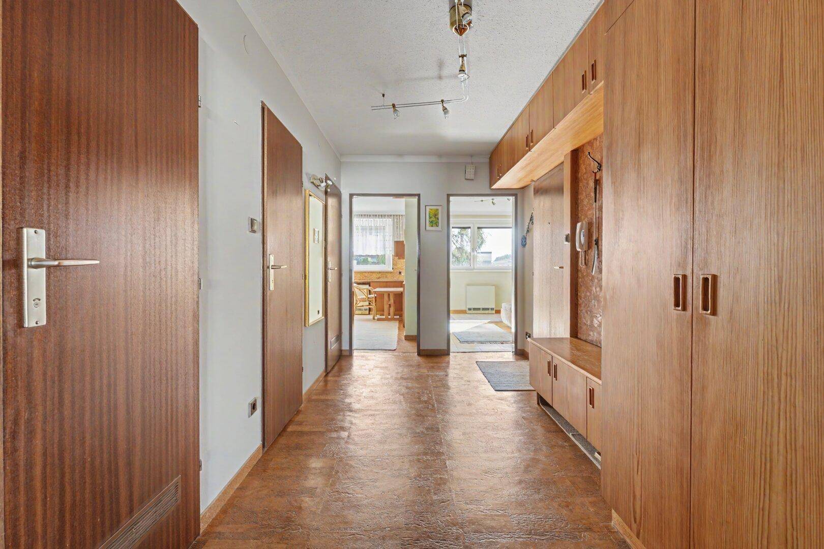 Langer Flur mit Holzvertäfelung, Einbauschränken und mehreren Zimmertüren.