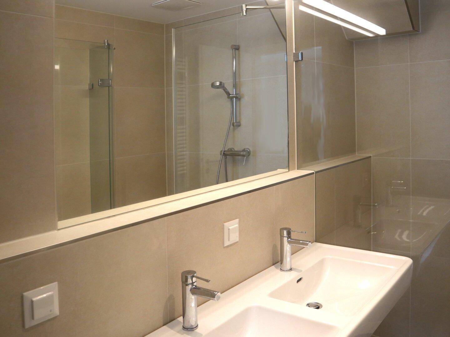 Modernes Badezimmer mit Doppelwaschbecken, großem Spiegel und begehbarer Dusche.