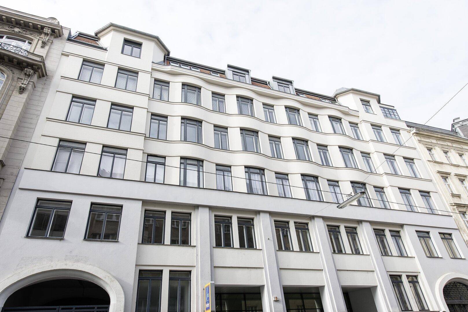 Mehrstöckiges Gebäude mit vielen Fenstern und einer modernen, hellen Fassade.
