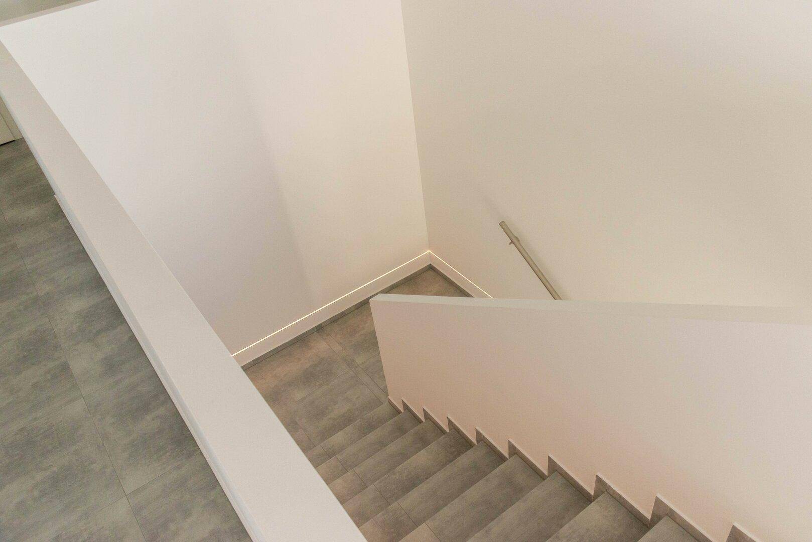 Treppenhaus mit schlichten Stufen und einem Handlauf, das zu den oberen Etagen führt.