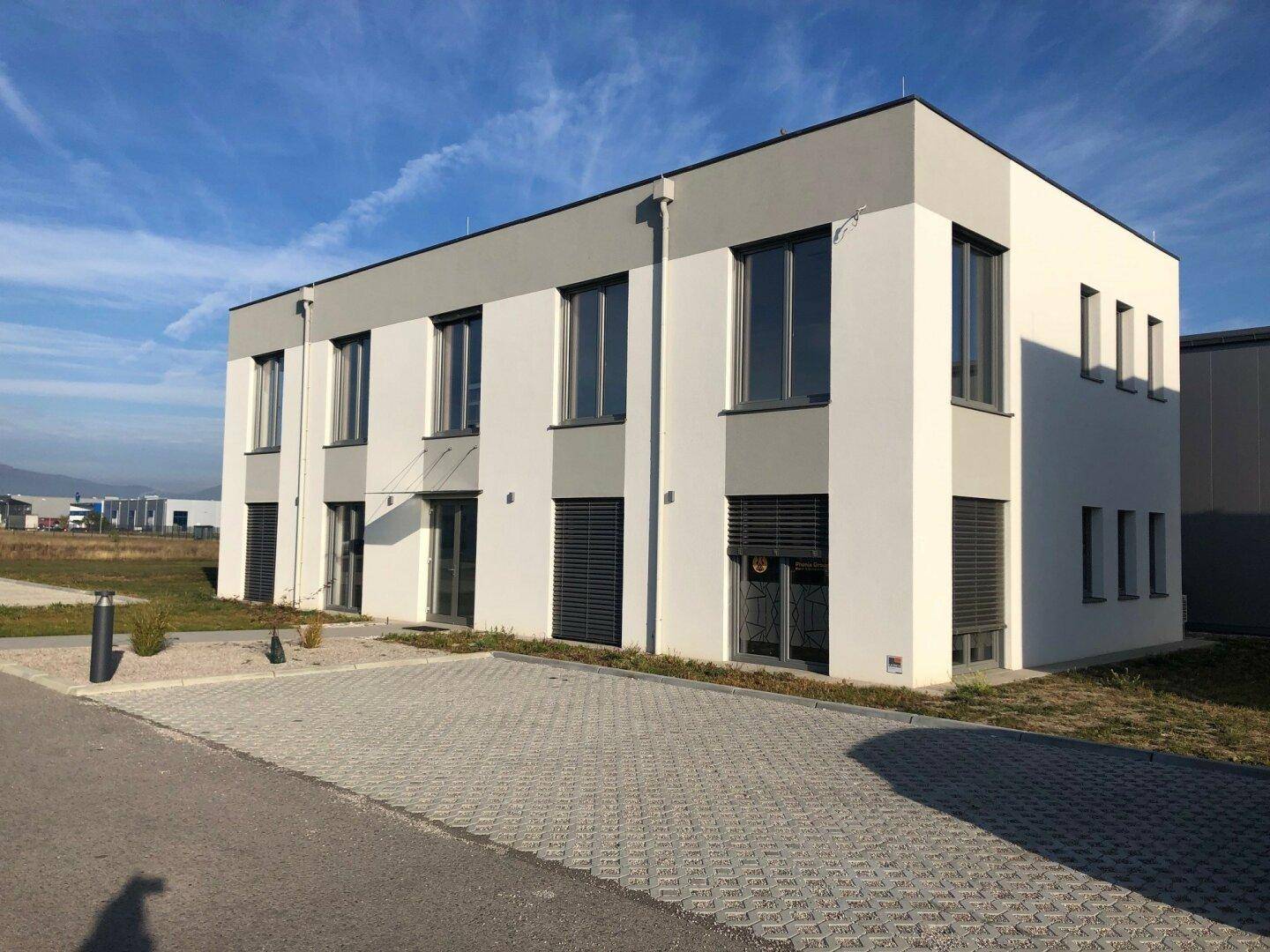 Ansicht eines modernen Bürogebäudes mit klaren Linien und großen Fenstern an einem sonnigen Tag.