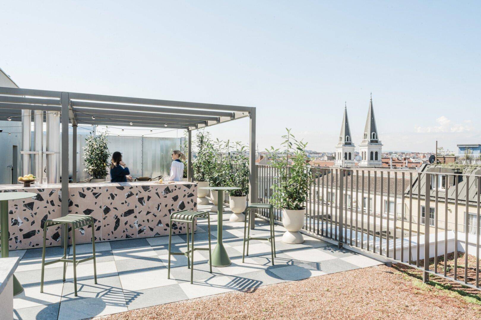 Geräumige Dachterrasse mit moderner Bar, Sitzgelegenheiten und weitem Stadtblick.