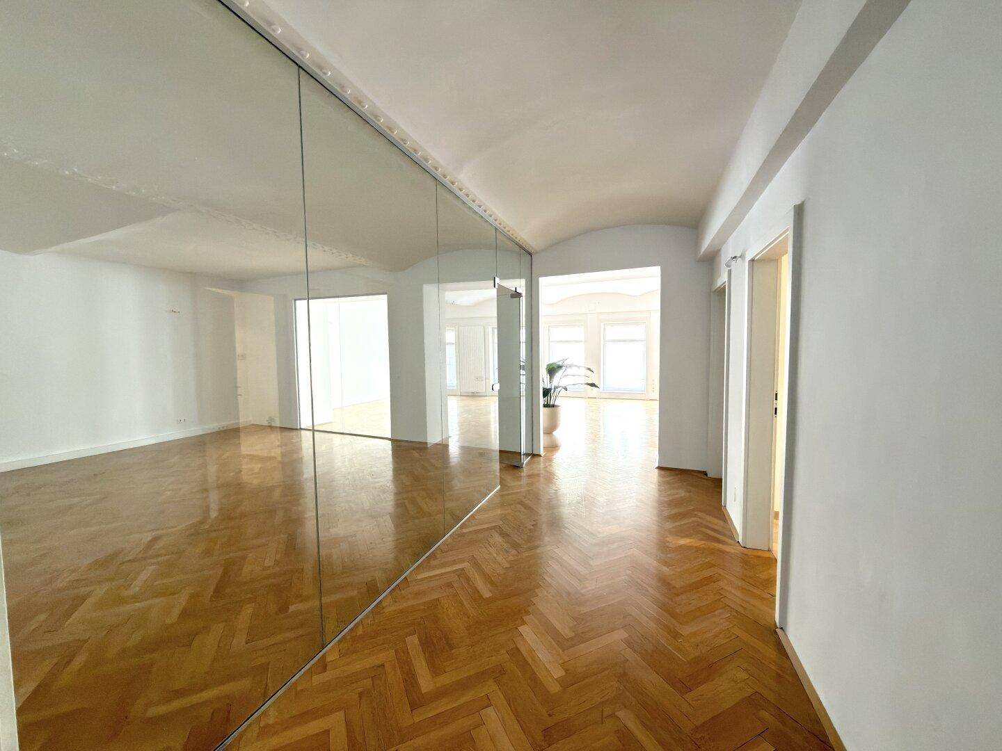 Heller Flur mit Fischgrätparkett und einer großen Spiegelfläche, die den Raum optisch erweitert.