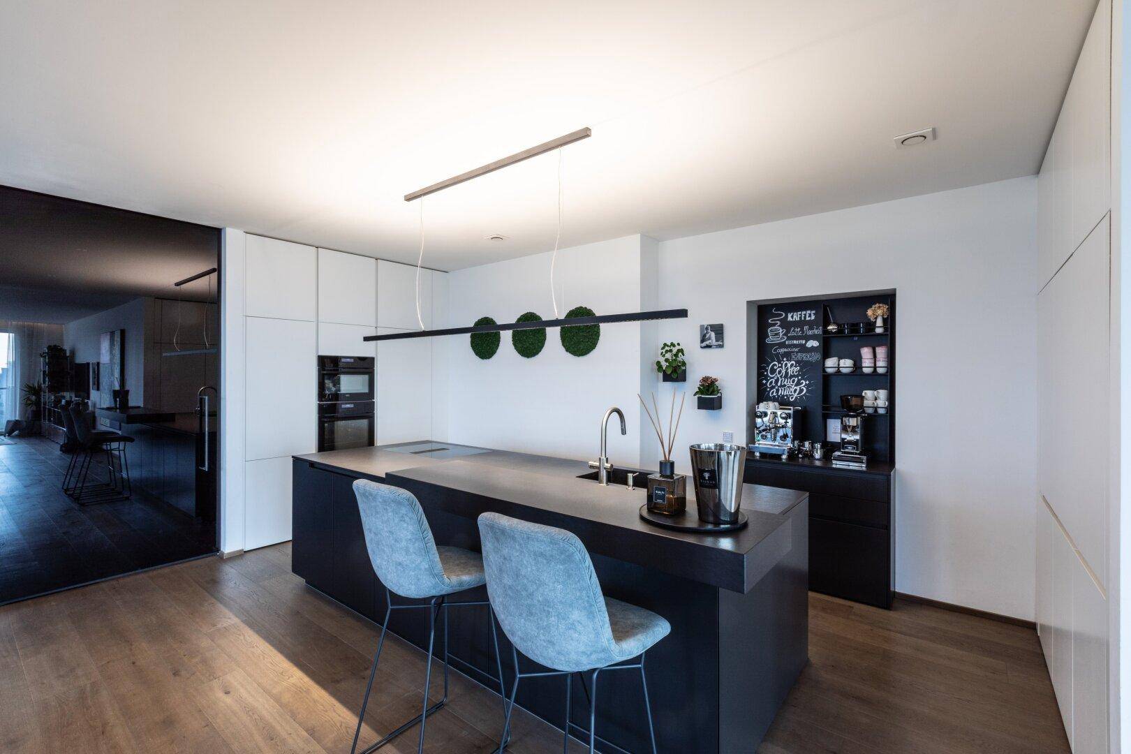 Moderne Küche mit dunkler Kücheninsel, integrierten Geräten und minimalistischem Design.