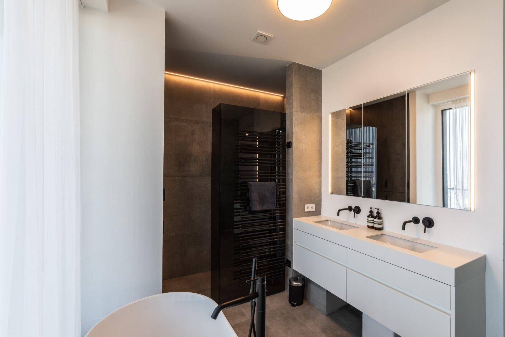 Elegantes Badezimmer mit Doppelwaschbecken, begehbarer Dusche und freistehender Badewanne.