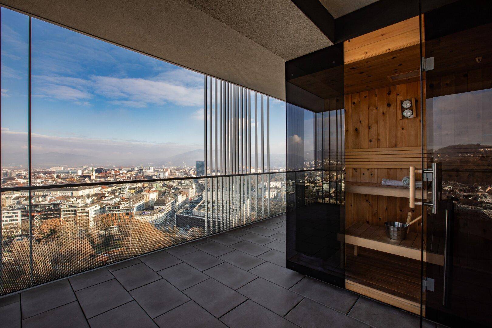 Sonniger Terrassenbereich mit privater Sauna und atemberaubendem Panoramablick auf die Stadt.