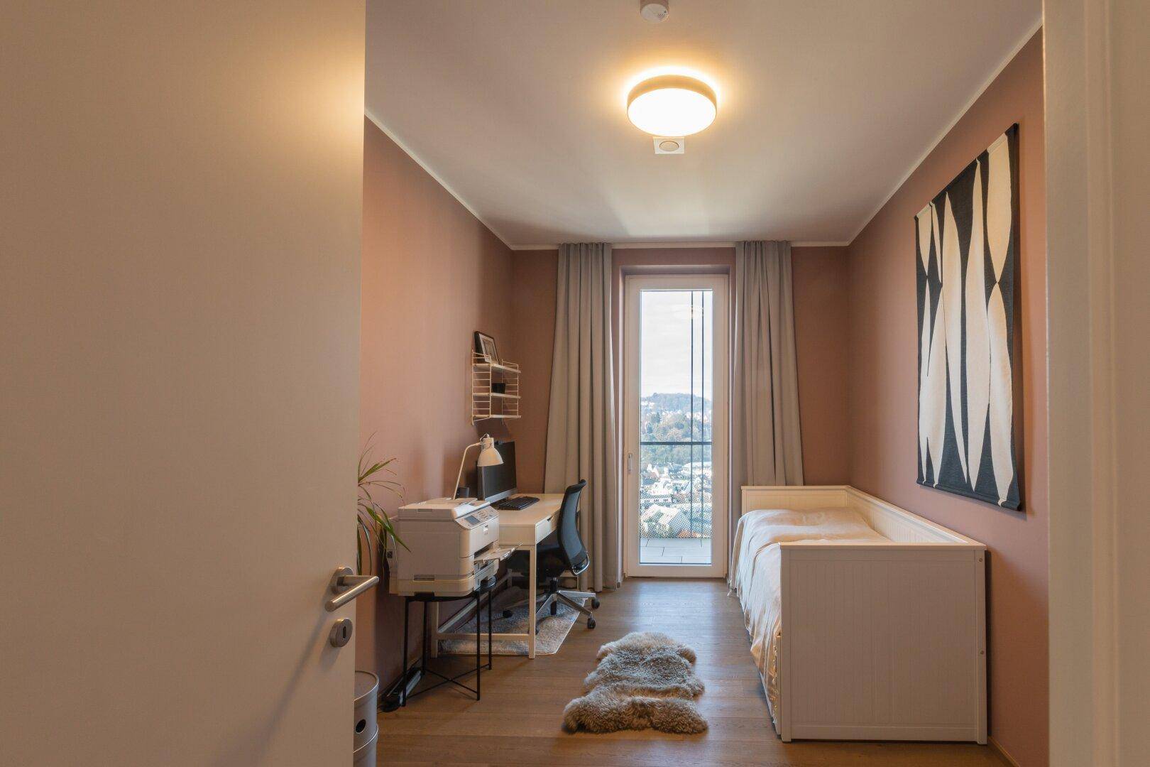 Helles Schlafzimmer oder Büro mit Schreibtisch, Bett und Ausblick auf die Umgebung.