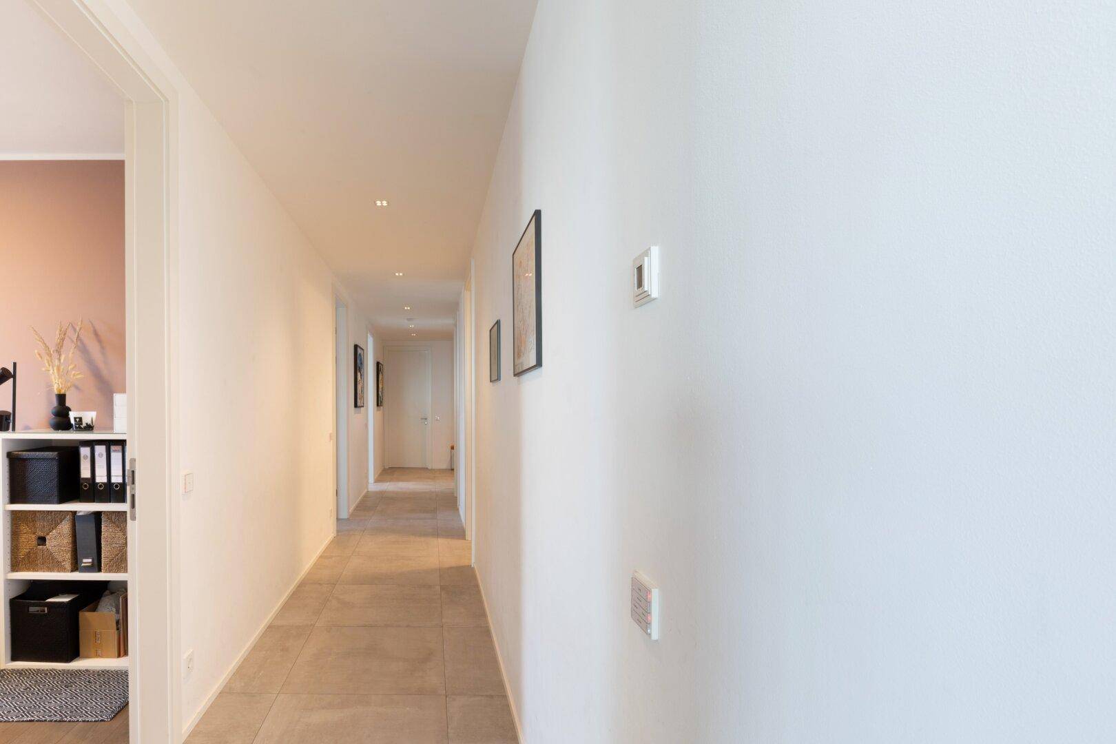 Langer, heller Flur mit Fliesenboden, der verschiedene Bereiche der Wohnung verbindet.