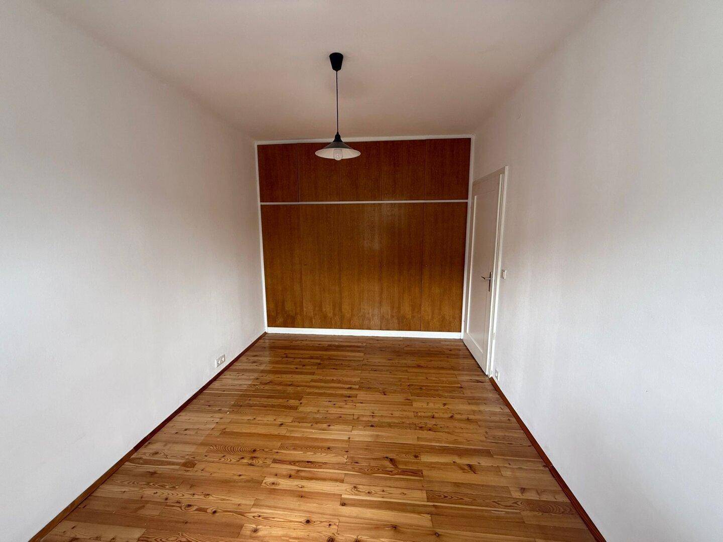 Schlafzimmer mit Holzfußboden und einer integrierten Holzschrankwand.