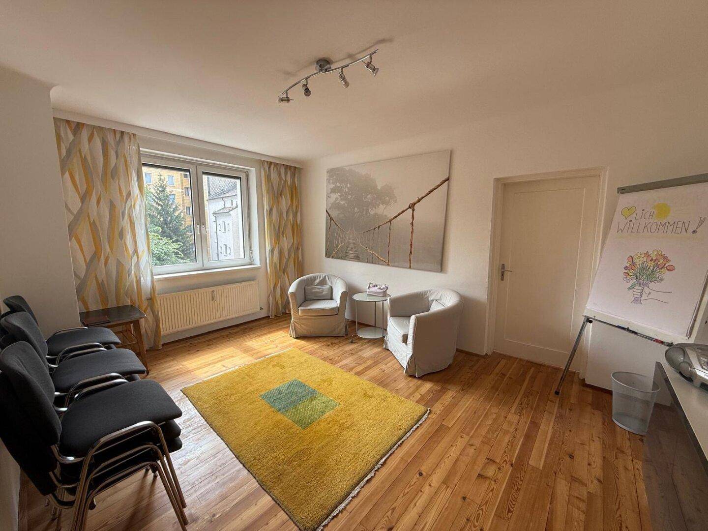 Helles Büro oder Besprechungszimmer mit Holzfußboden, gelbem Teppich und bequemen Sesseln.