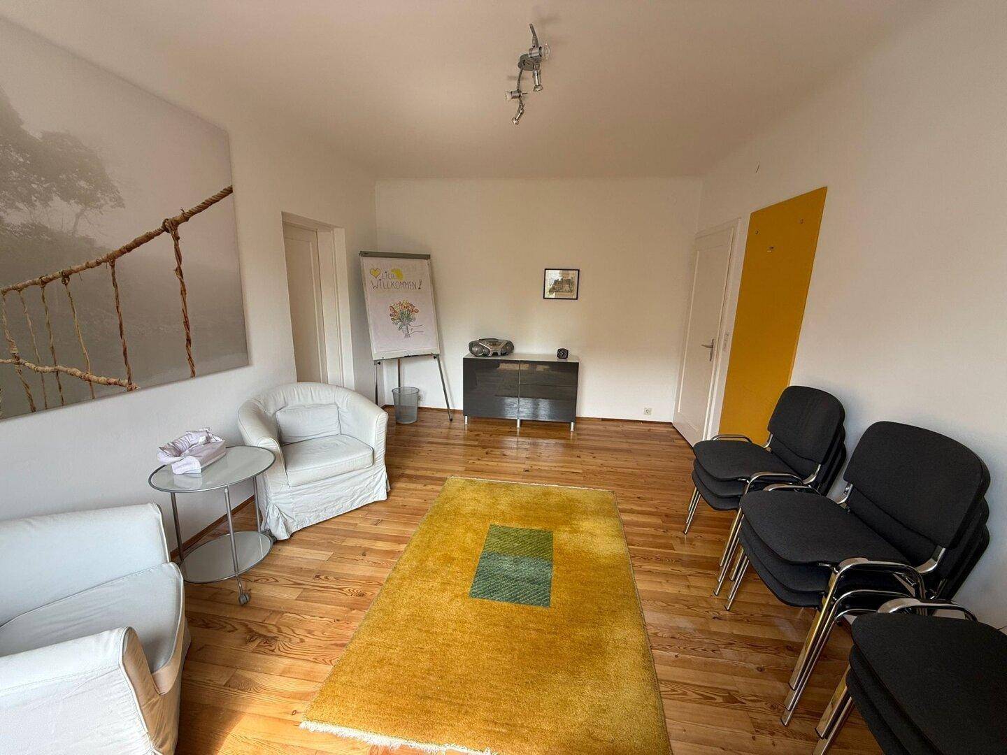 Geräumiges Büro mit Holzfußboden, gelbem Teppich, Schrank und Whiteboard für Präsentationen.