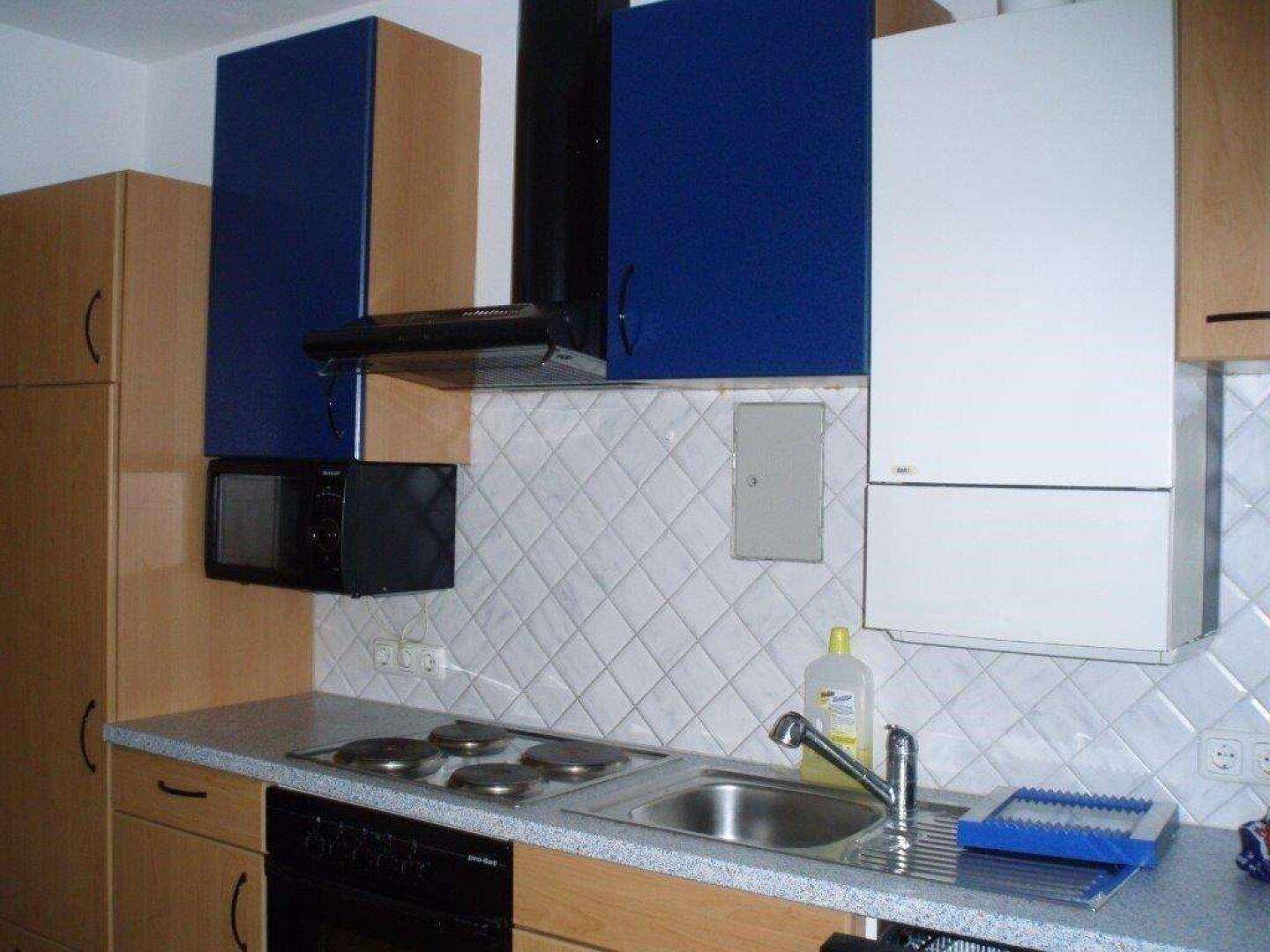 Küche mit Holzschränken, blauen Oberschränken und integrierten Kochgeräten.