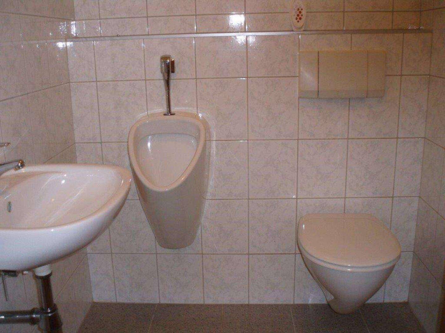 Kleines WC mit Urinal, Toilette und Waschbecken, komplett gefliest.