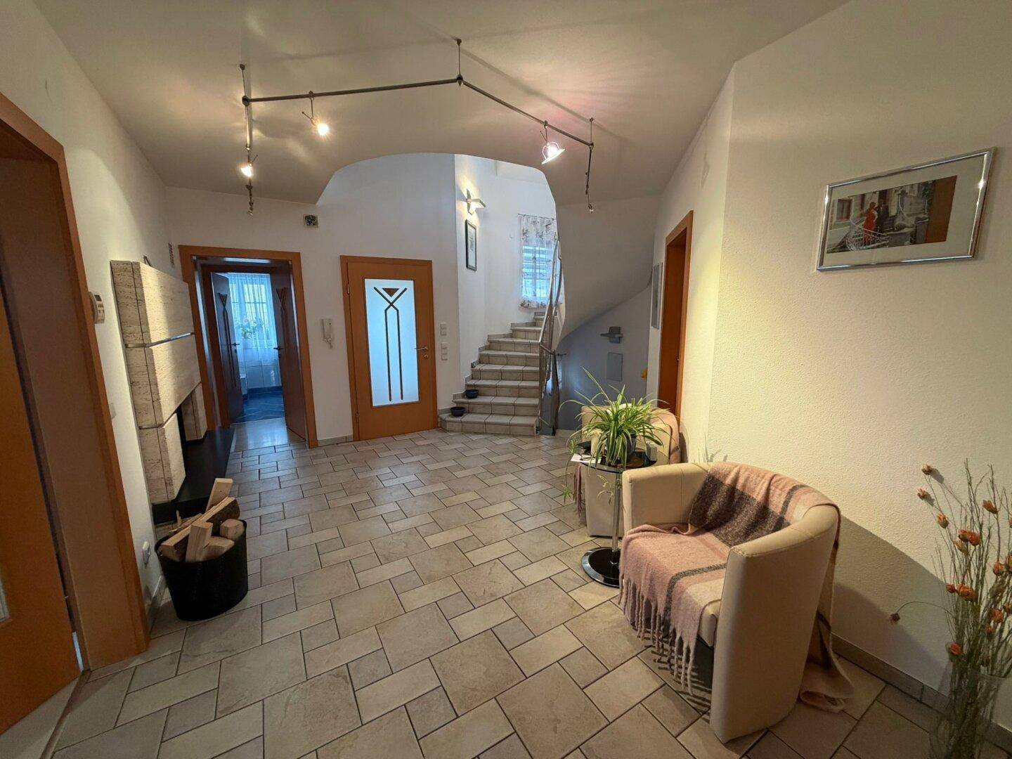 Geräumiger Flur mit Fliesenboden, Sitzgelegenheit und Treppenaufgang zum Obergeschoss.
