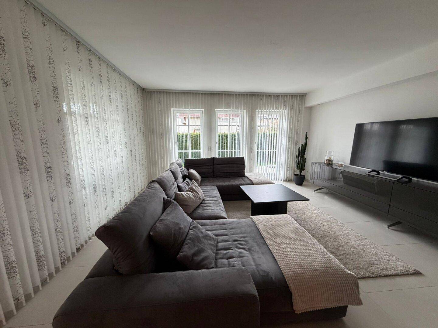 Modernes Wohnzimmer mit großem Ecksofa, Flachbildfernseher und stilvoller Dekoration.