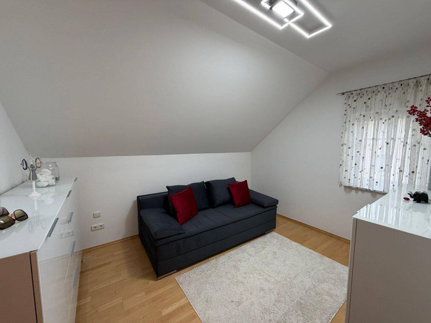 Gemütliches Schlafzimmer mit Schlafsofa, Kommode und Dachschräge.