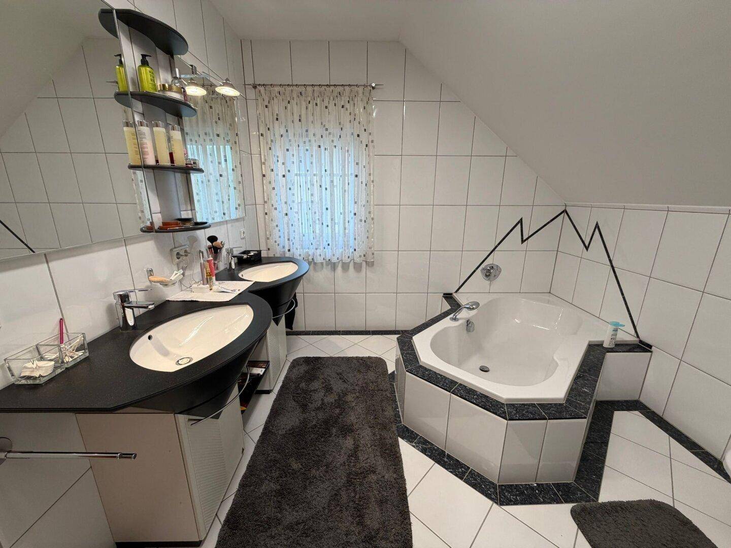 Badezimmer im Dachgeschoss mit Eckbadewanne, Doppelwaschbecken und Dachschräge.