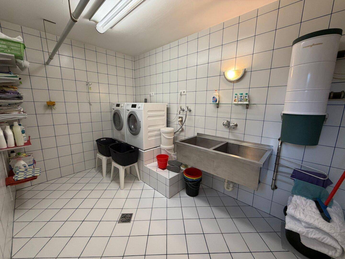 Praktischer Hauswirtschaftsraum mit Waschmaschinen, Doppelwaschbecken und Fliesenboden.