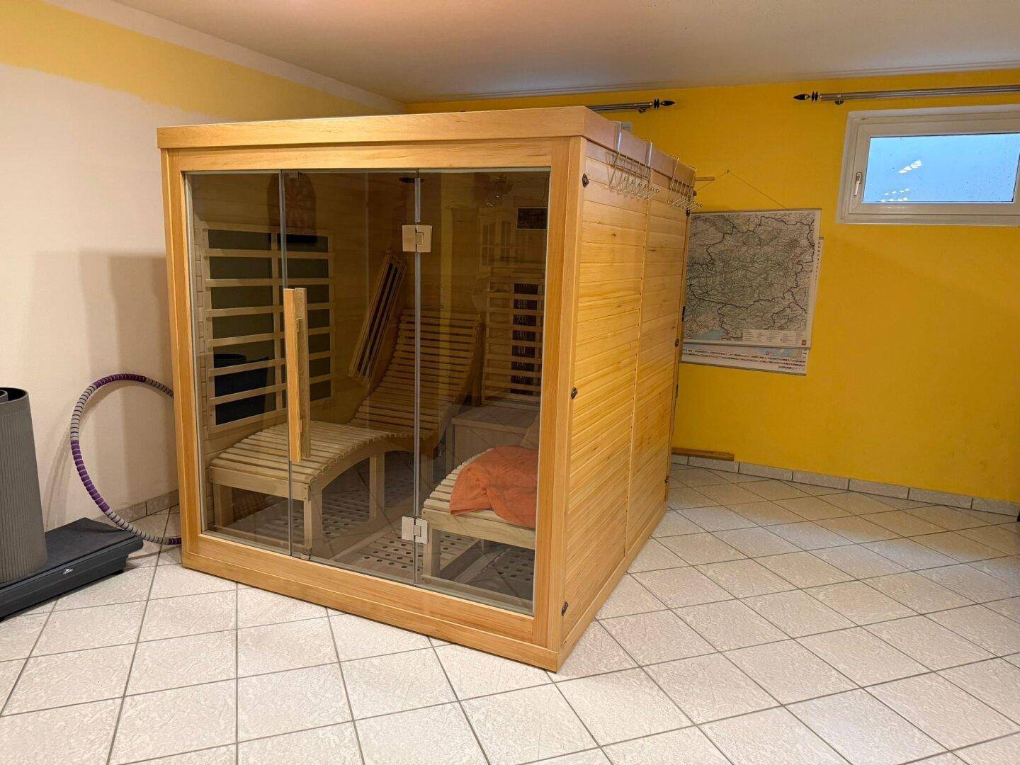 Wellnessbereich mit moderner Saunakabine, Fliesenboden und gelben Wänden.