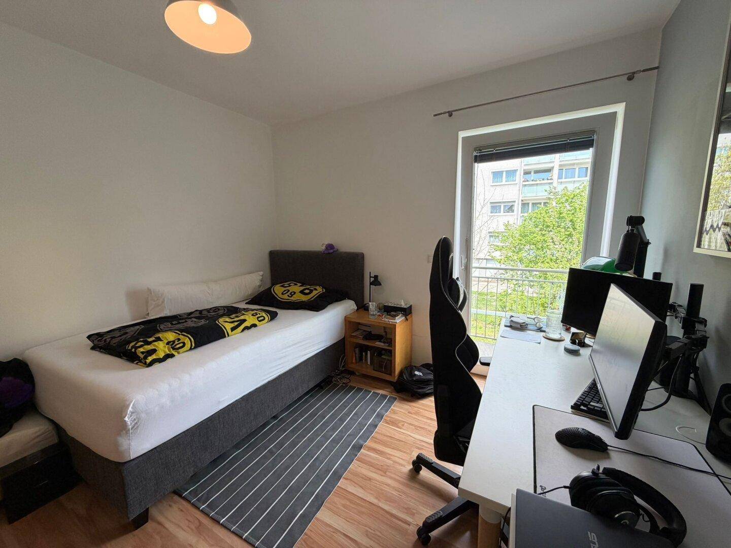 Jugendzimmer mit Bett, Schreibtisch und Laminatboden, bietet einen grünen Ausblick.