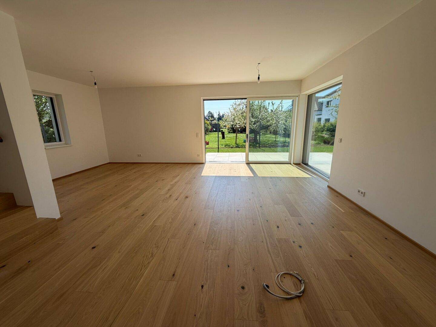 Lichtdurchflutetes Wohnzimmer mit Eichenparkettboden und direktem Zugang zum Garten.