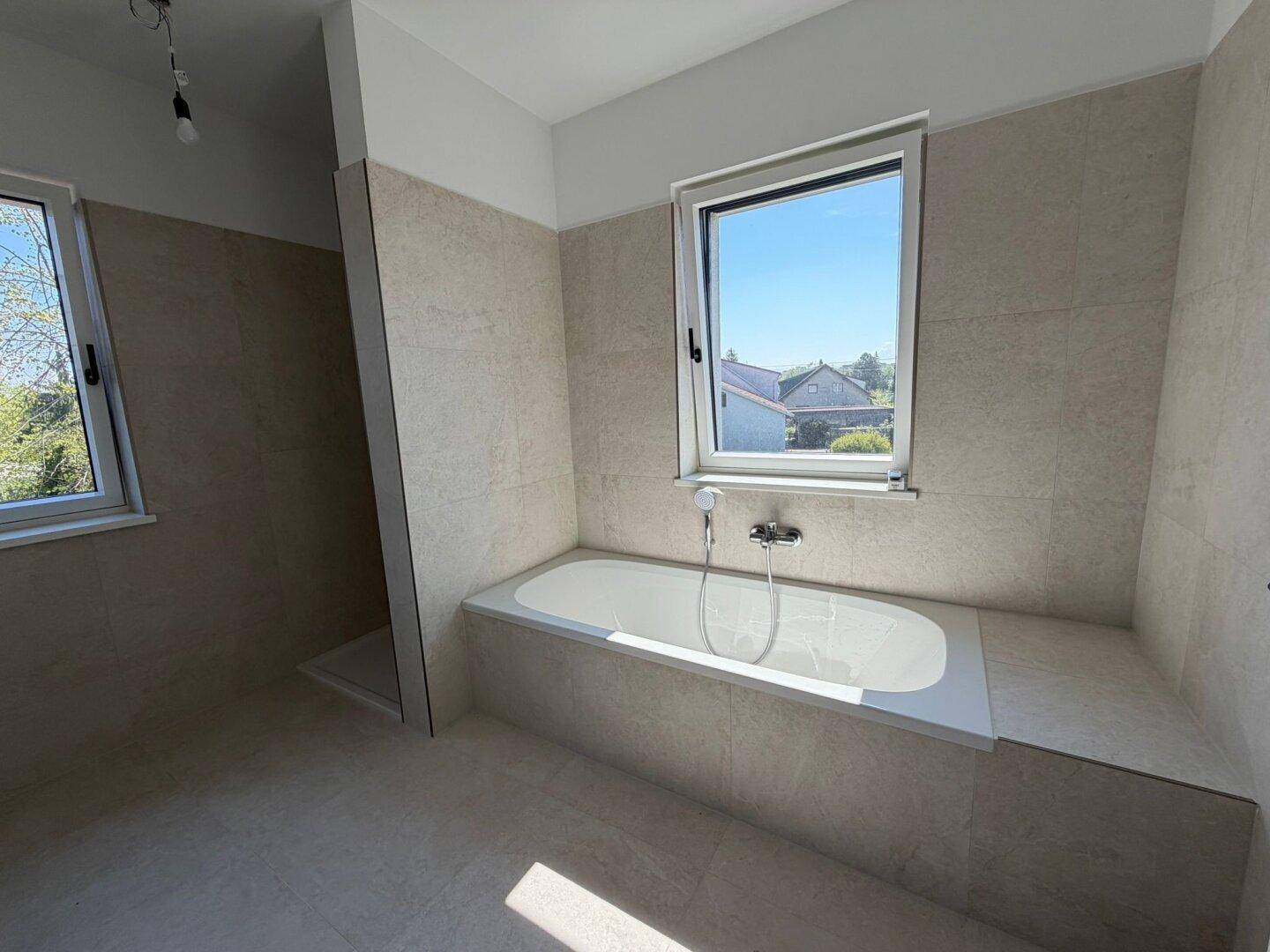 Modernes Badezimmer mit Badewanne, begehbarer Dusche und Fenster für Tageslicht.