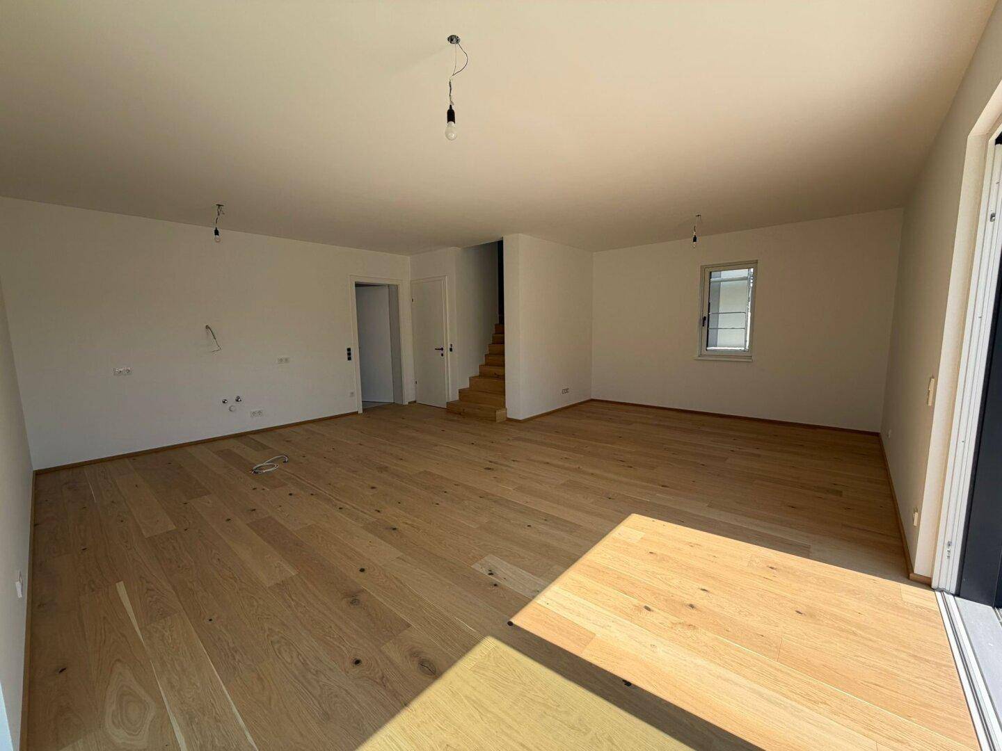 Heller Wohnbereich mit Eichenparkett und Treppe zum Obergeschoss, bereit für individuelle Gestaltung.