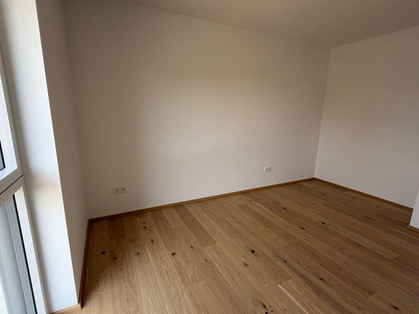 Ruhiges Schlafzimmer mit Eichenparkettboden und viel Tageslicht, ideal zum Entspannen.