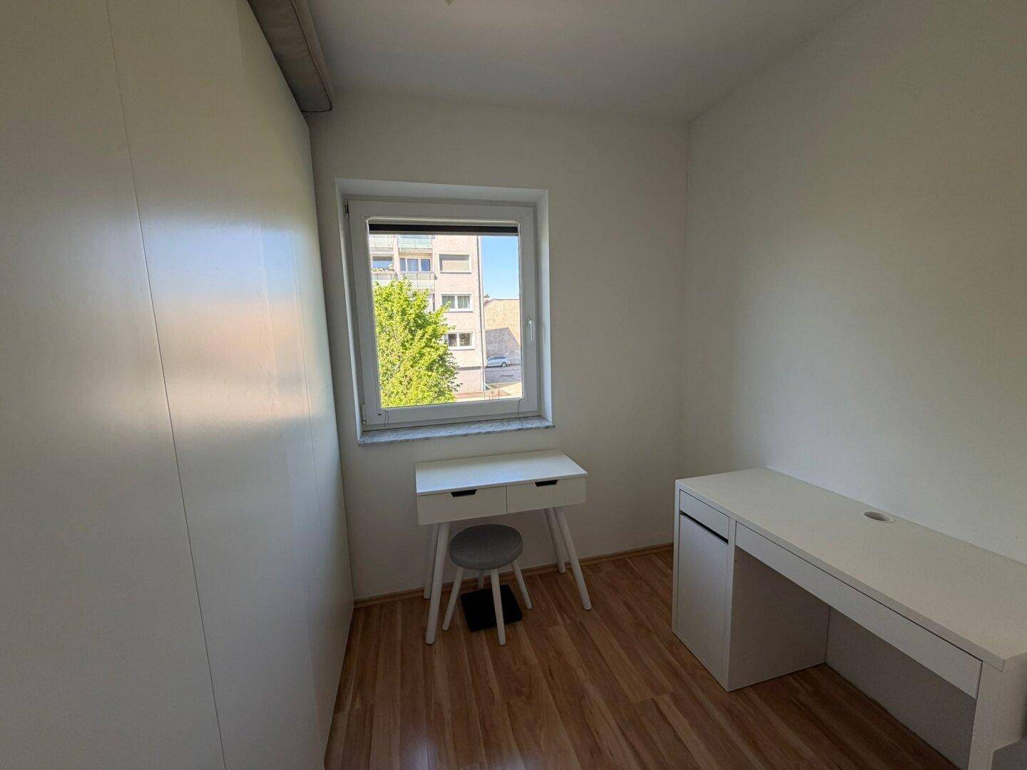 Kleines Büro oder Arbeitszimmer mit Laminatboden, Schreibtisch und Einbauschrank.
