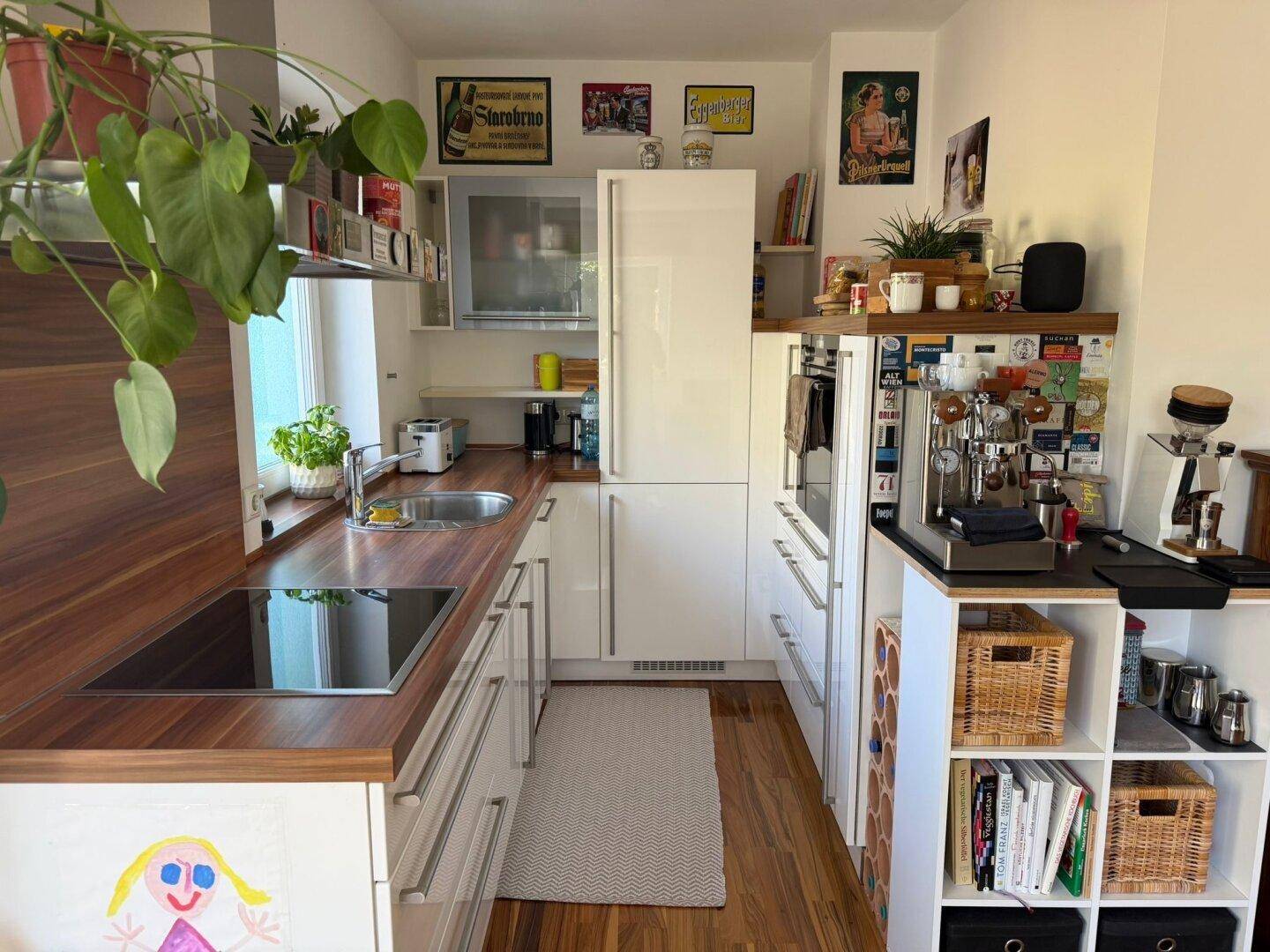 Moderne Einbauküche mit weißen Fronten, Holz-Arbeitsplatten und integrierten Geräten.