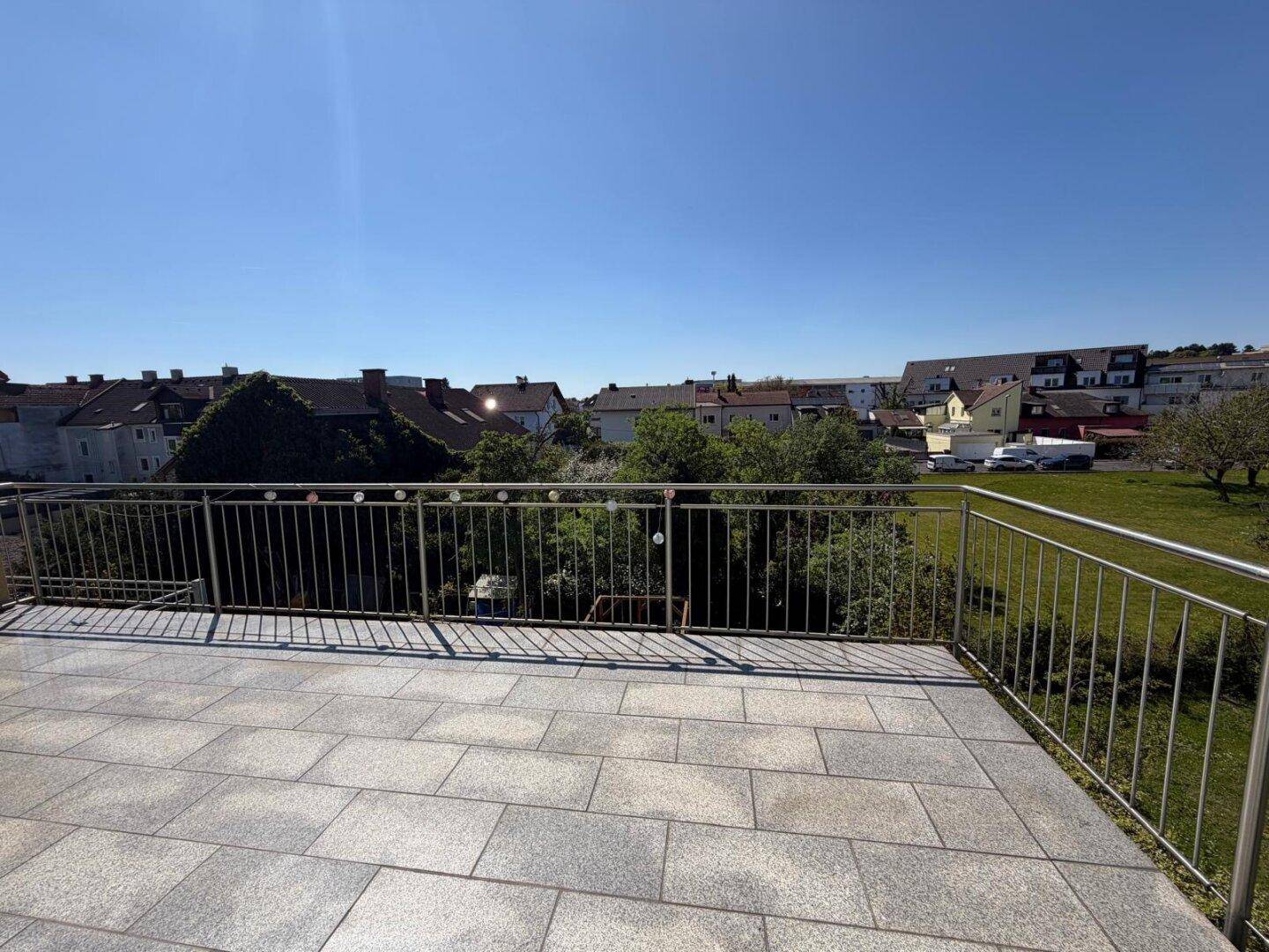 Weitläufige Dachterrasse mit Fliesenboden und Panoramablick über die Stadt und Umgebung.