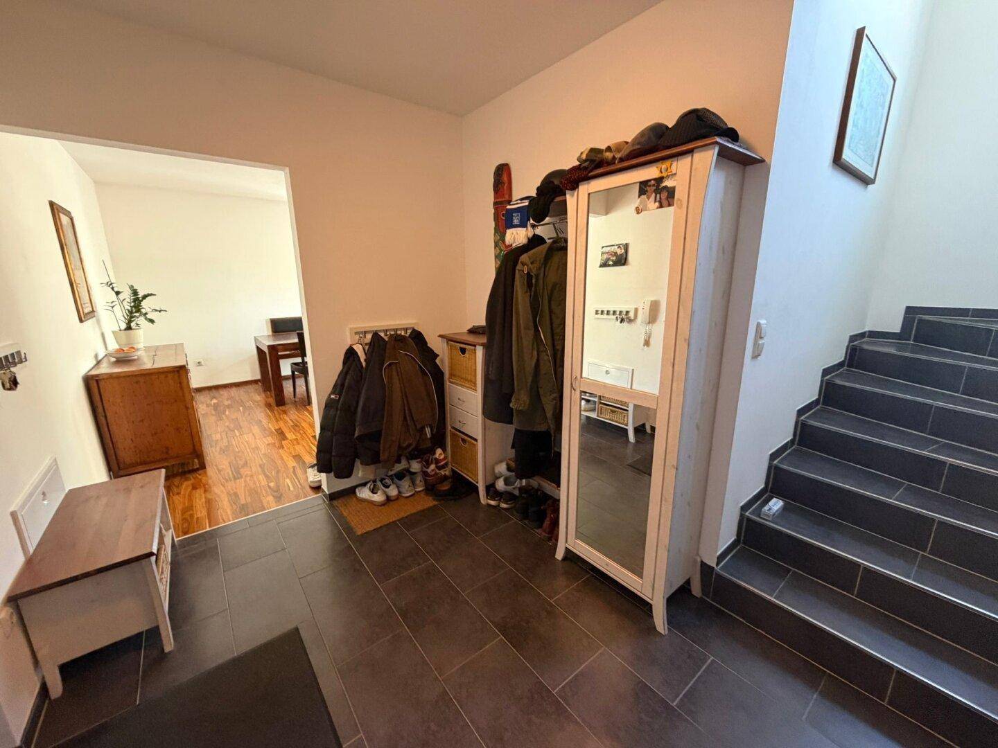 Eingangsbereich mit dunklen Fliesen, Garderobe und Treppe zu den oberen Etagen.