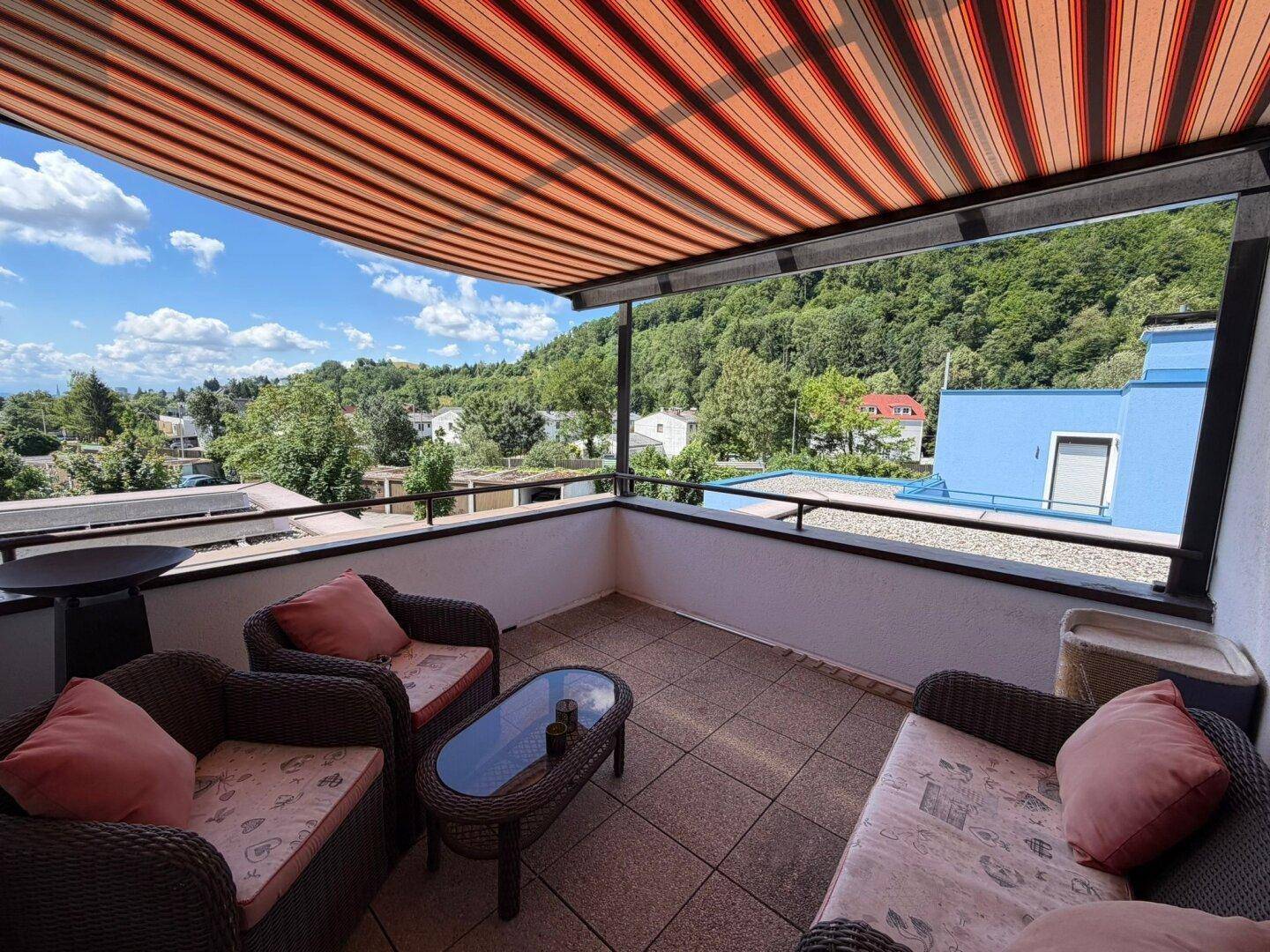Großer Balkon mit Markise, Sitzmöbeln und weitem Blick ins Grüne.