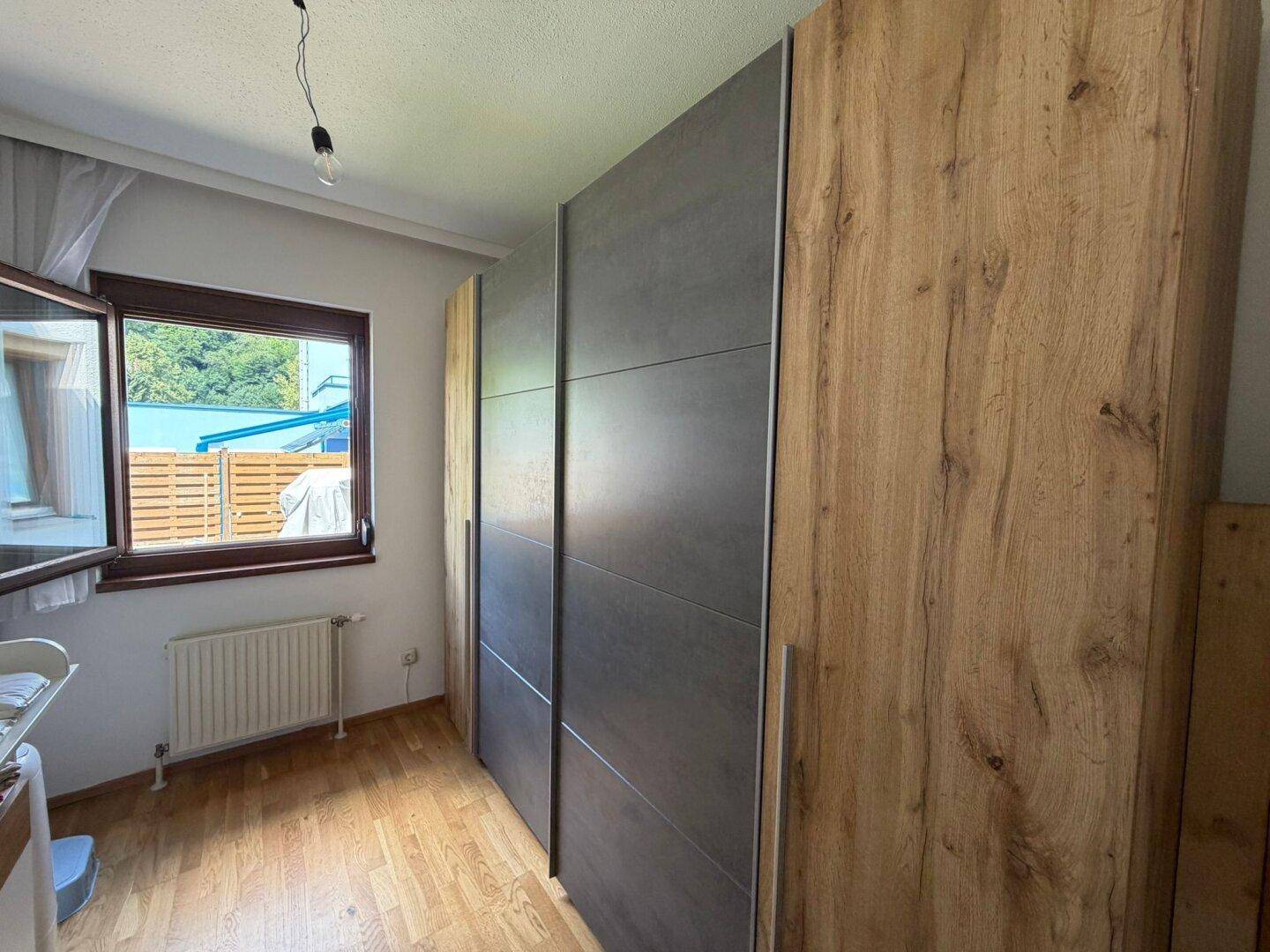 Schlafzimmer mit großem Kleiderschrank und Fenster.